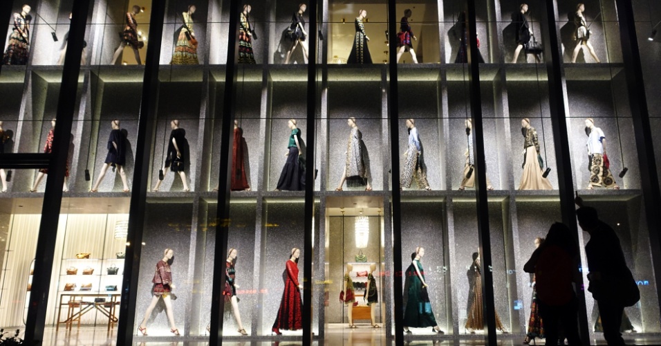 21.jul.2014 - Casal observa roupas exibidas na vitrine de uma loja em Xangai, na China