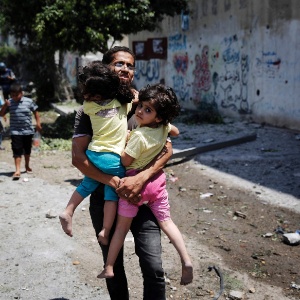 20.jul.2014 - Palestino carrega criança enquanto foge do bairro Shejaia, na faixa de Gaza, durante bombardeio israelense - Finbarr O"Reilly/Reuters