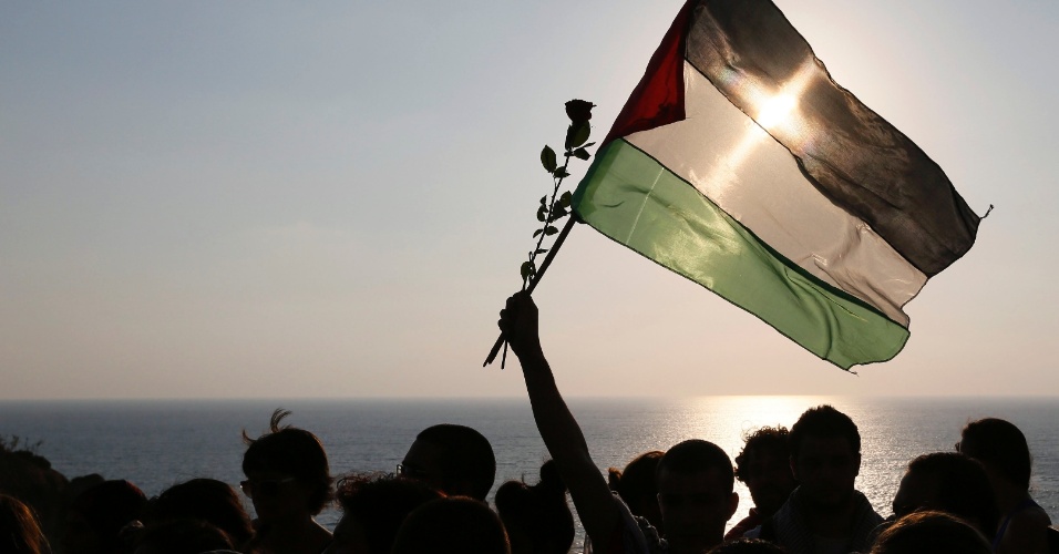 22.jul.2014 - Manifestante balança bandeira palestina durante protesto pacífico contra a ação militar de Israel em Gaza, em Beirute, no Líbano