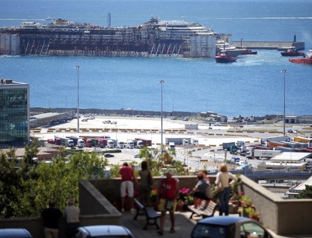 27.jul.2014 - Moradores de Gênova assistem à chegada do navio Costa Concordia ao porto da cidade. A embarcação de 114 mil toneladas foi rebocada por 330 quilômetros desde a ilha de Giglio - Marco Bertorello/AFP