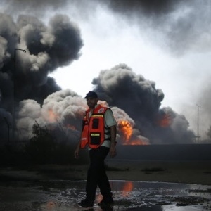 Um bombeiro palestino trabalha para conter um incêndio no depósito de combustível da única usina de energia da faixa de Gaza, que segundo testemunhas, foi atingido por disparos do Exército israelense - Mohammed Salem/Reuters