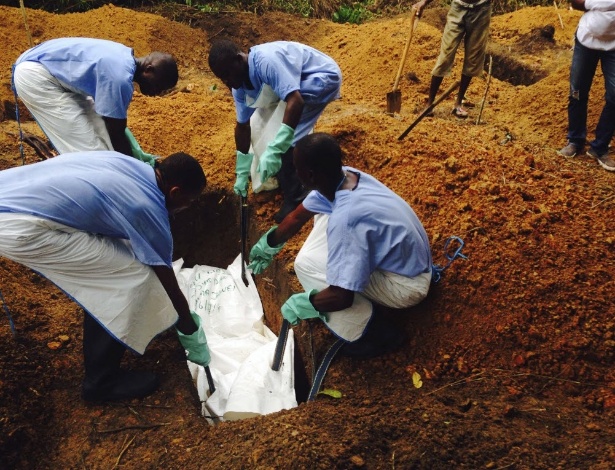 Voluntários baixam um corpo que foi preparado dentro das práticas de sepultamento seguro para evitar o risco de contágio de ebola, em uma sepultura em Kailahun, em Serra Leoa, nesta terça-feira (5) - Tarik Jasarevic/Distribuída pela Reuters