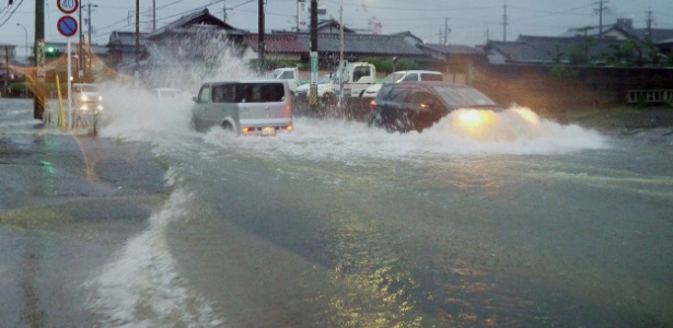 Carros tentam passar em rua alagada pelo tufão Halong, na cidade de Tsu, Japão - Jiji Press/AFP