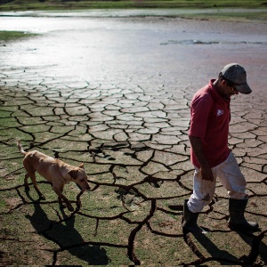 Morador caminha com um cachorro ao longo da margem seca da represa Paraibuna - Roosevelt Cassio/Reuters