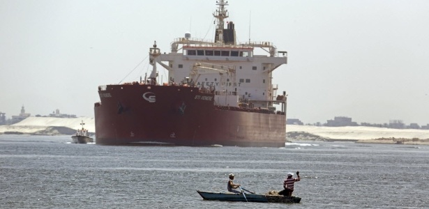 Egípcios pescam em frente de um navio maltês que cruza o canal de Suez, em Ismailia - Amr Nabil/AFP