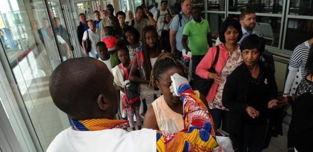 Médico do Instituto Nacional de Saúde Pública controla a temperatura das pessoas no aeroporto, em Abidjan, na Costa do Marfim - Sia Kambou/AFP
