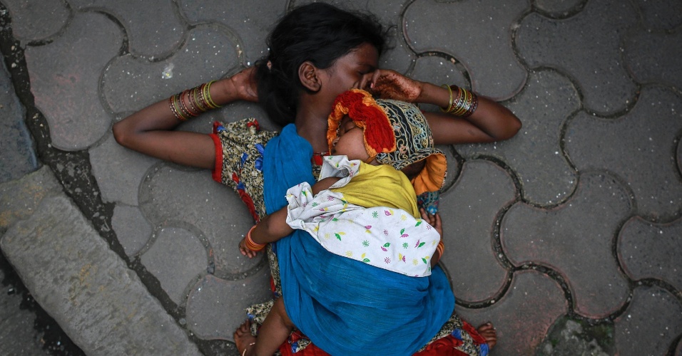 13.ago.2014 - Uma mulher dorme com seu bebê na calçada de um mercado em Mumbai, na Índia