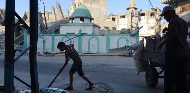 Menino e pai varrem o lixo na rua diante da mesquita de Omari, em Jabaliya, no norte da faixa de Gaza; o local, bombardeado por Israel, abrigava uma mesquita desde o século 7 e partes do templo datavam do século 14
