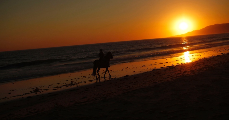 14.ago.2014 - Cavaleiro segue ao longo da praia de Los Lances durante o pôr do sol em Tarifa, perto de Cadiz, na Espanha