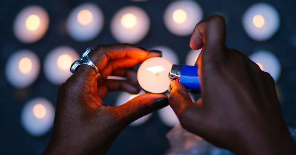 15.ago.2014 - Mulher acende uma vela durante uma vigília para homenagear Michael Brown, um rapaz que foi baleado e morto por um policial não identificado no último sábado em Ferguson, em Nova York (EUA)