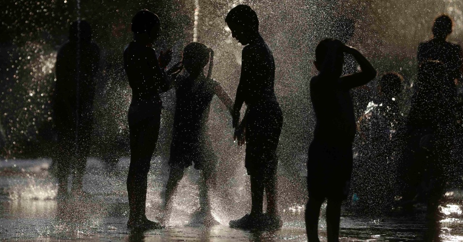 18.ago.2014 - Crianças brincam em uma fonte para se refrescar, junto ao rio Manzanares em Madri, na Espanha