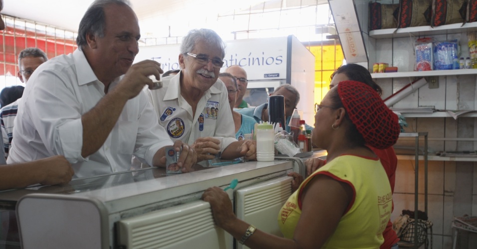 25.ago.2014 - O candidato ao governo do Rio de Janeiro pelo PMDB, Luiz Fernando Pezão, toma café durante visita à favela do Batan, na zona oeste do Rio, em evento de campanha na manhã desta segunda-feira (25)