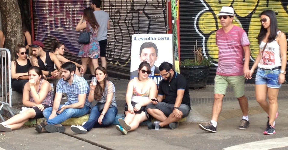 Visitantes da Feira da Vila Madalena descansam entre barracas e propagandas políticas em rua do bairro paulistano