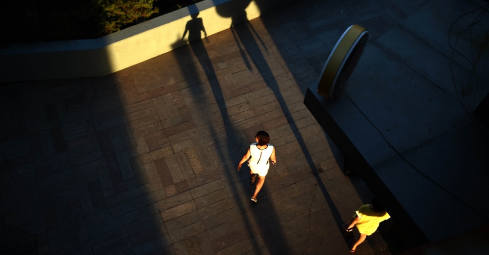 26.ago.2014 - Duas mulheres caminham diante de um centro comercial em Pequim, na China