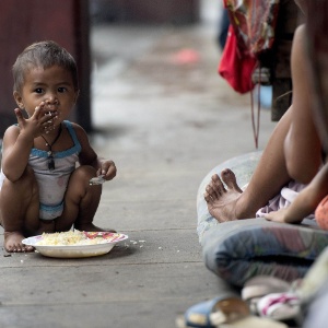 Criança sem-teto come arroz na calçada em Manila, nas Filipinas - Noel Celis/AFP