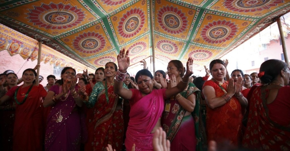28.ago.2014 - Mulheres cantam e dançam no templo de Pashupatinath, durante o festival Teej em Katmandu, no Nepal, nesta quinta-feira (28). O festival de três dias, que comemora a união das deusas Parvati e Shiva, envolve festas suntuosas e jejum rígido. As mulheres hindus rezam para a felicidade conjugal, o bem-estar de seus familiares e a purificação de seus próprios corpos e almas