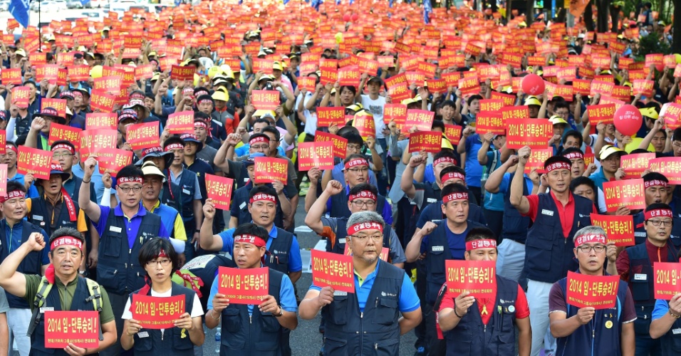 28.ago.2014 - Trabalhadores sul-coreanos seguram cartazes com o texto "Vitória em nossa luta por salários melhores!" durante manifestação em frente à sede da Kia, em Seul. Milhares de trabalhadores do grupo automotivo iniciaram greve