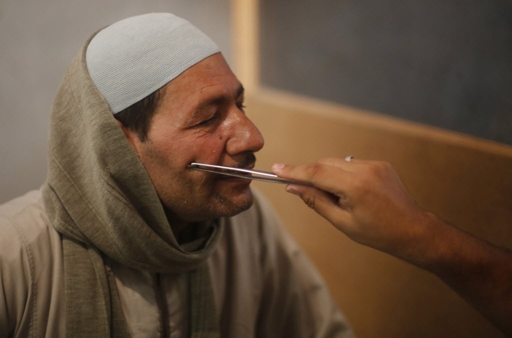 1º.set.2014 - Haj Saied Al Sayeeh coloca uma abelha no rosto de um homem, que sofre de uma doença no nervo facial, no centro do Cairo (Egito). Al Sayeeh acredita que o veneno das abelhas tem propriedades especiais, que, quando utilizadas em partes específicas do corpo, pode curar doenças como problemas renais, apendicite e até câncer - Amr Abdallah Dalsh/Reuters