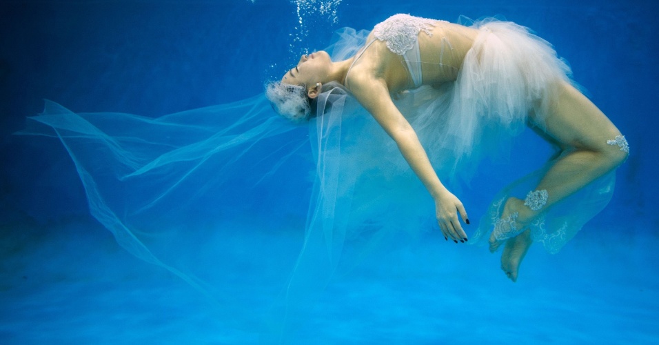 04.set.2014 - Mulher vestida com roupa inspirada em um vestido de noiva realiza sessão de fotos embaixo d'água, em Xangai, na China, nesta quinta-feira (4)
