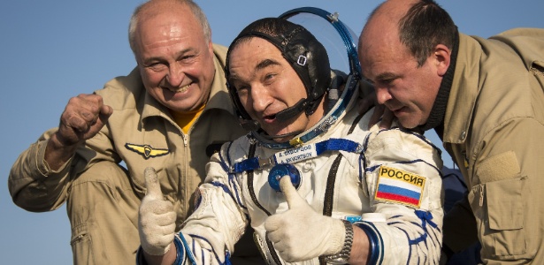 Alexander Skvortsov, cosmonauta russo, acena enquanto recebe ajuda para sair da capsula Soyuz logo após a aterrisagem, no deserto no Cazaquistão - Nasa/AFP