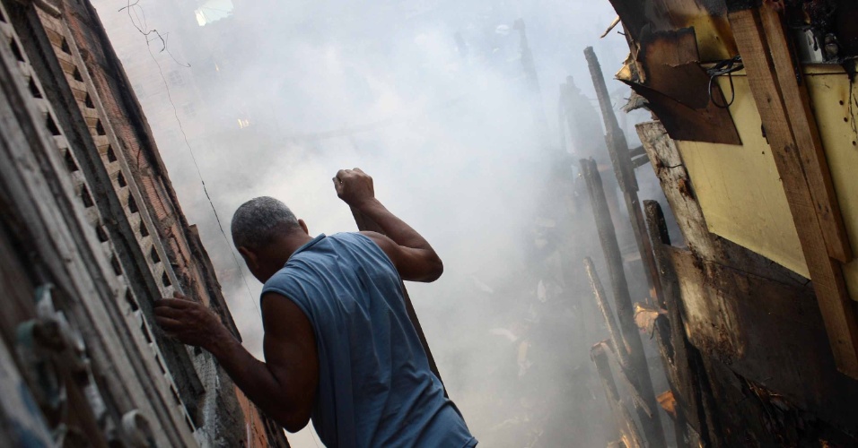 11.set.2014 - Morador observa um incêndio de grandes proporções que atingiu parte de uma favela na região do Rio Pequeno, na zona oeste de São Paulo, na tarde desta quinta-feira (11). Por volta das 17h20, o fogo já tinha sido contido e um grupo de moradores protestava na região