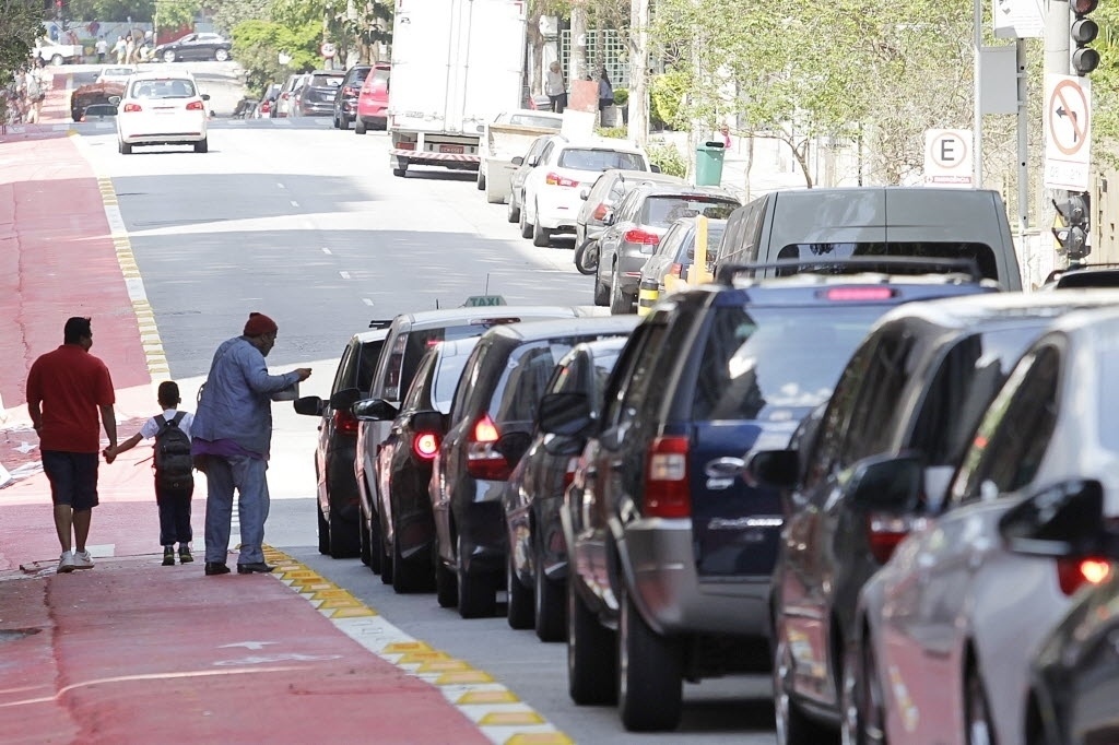 11.set.2014 - Pedestres desembarcam de carros em trecho da ciclovia Pacaembu na rua Piauí, em Higienópolis, zona central de São Paulo. Em vários trechos, carros invadem a ciclovia em conversões ou para acessar garagens, às vésperas da inauguração do novo trecho de ciclovias em São Paulo - Reinaldo Canato/UOL