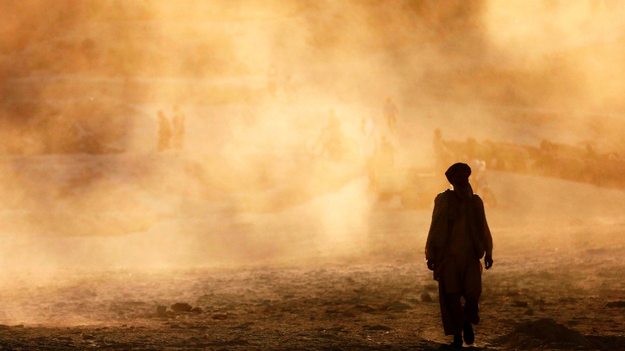 17.set.2014 - Homem caminha com nuvem de poeira ao fundo, durante o pôr-do-sol na cidade de Cabul, no Afeganistão - Mohammad Ismali/Reuters