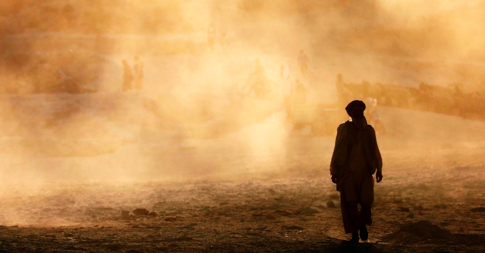 17.set.2014 - Homem caminha com nuvem de poeira ao fundo, durante o pôr-do-sol na cidade de Cabul, no Afeganistão