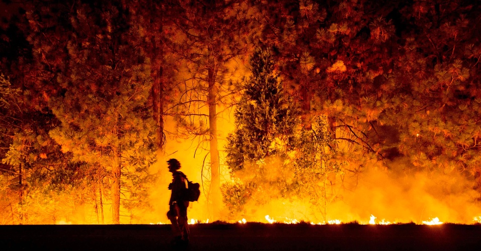 17.set.2014 - Bombeiro caminha diante da cortina de fogo causada por um incêndio na Highway 50, em Fresh Pond, na Califórnia (EUA)