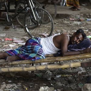 Homem descansa sobre carrinho de coleta de lixo em Dacca, no Bangladesh - Munir uz Zaman/AFP