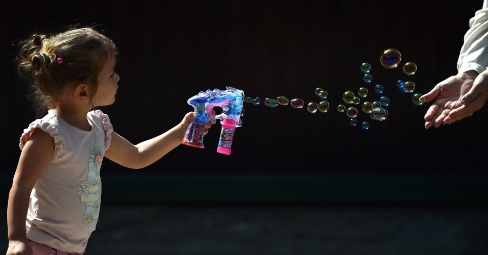 21.set.2014 - Menina brinca com bolhas de sabão na rua, em Milão, na Itália, neste domingo (21)