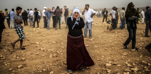 24.set.2014 - Uma mulher síria curda em tempestade de areia em uma colina onde e ela e outras pessoas observavam confrontos entre jihadistas do Estado Islâmico e combatentes curdos, no vilarejo de Swedi, a 10 km a oeste de Suruc, na província de Sanliurfa, na Síria - Bulent Kilic/AFP