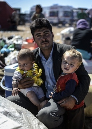 Família curda síria espera o momento de atravessar a fronteira para a Turquia - Bulent Kilic/ AFP
