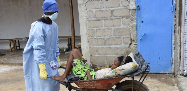 Homem leva mulher com ebola em Monrovia, na Libéria - Pascal Guyot/AFP