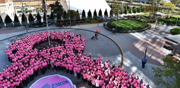 7.out.2014 - Voluntários vestem camisas e capacetes cor de rosa e formam o símbolo da campanha para estimular mulheres a fazerem os exames que detectam o câncer de mama, em Nova York (EUA) - Jewel Samad/AFP