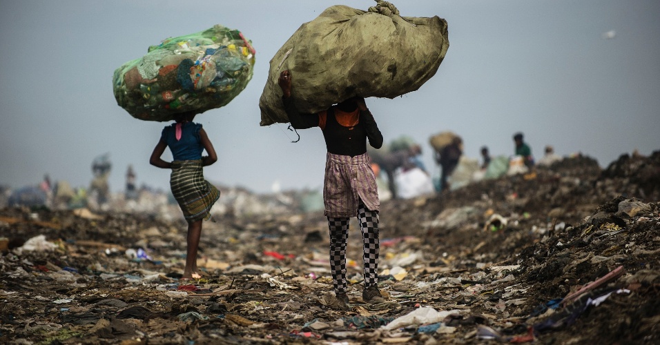 14.out.2014 - Meninas catadoras de lixo carregam sacos de itens de plástico e latas recolhidos no lixo municipal de Maputo, em Moçambique