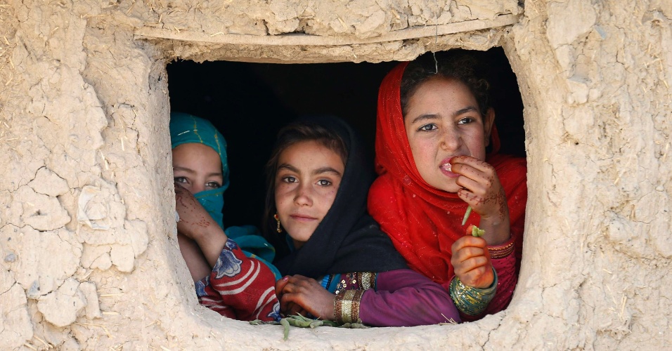 14.out.2014 - Meninas refugiadas afegãs olham para fora de seu abrigo em um campo de refugiados em Cabul, no Afeganistão