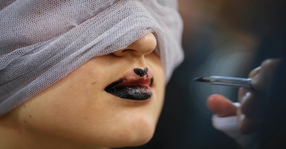 16.out.2014 - Modelo tem a maquiagem feita nos bastidores de desfile, durante a Semana de Moda de Kiev, na Ucrânia