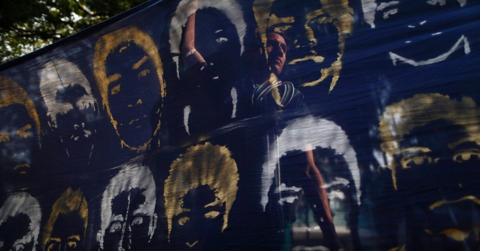 16.out.2014 - Um manifestante é visto atrás de uma bandeira representando rostos dos alunos desaparecidos da Escola Normal Rural Raúl Isidro Burgos, em Ayotzinapa, durante um protesto em frente ao prédio do escritório do procurador-geral do México, na capital do país