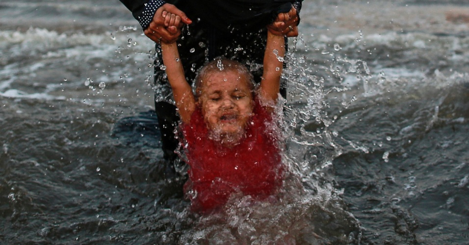 17.out.2014 - Mãe segura criança pelas mãos em praia no Mar da Arábia em Mumbai, na Índia