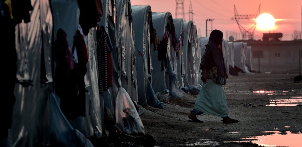 Mulher curda síria caminha em um campo de refugiados na Turquia, na fronteira com a Síria - Aris Messinis/AFP