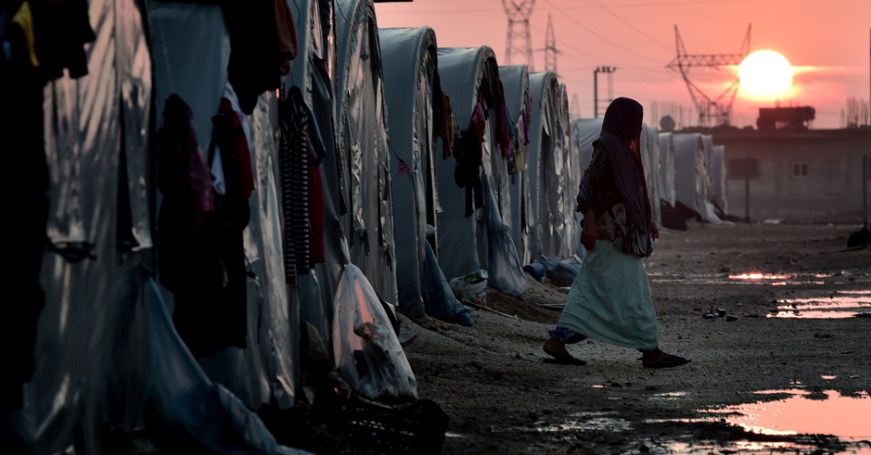 17.out.2014 - Mulher curda síria caminha em um campo de refugiados na Turquia, durante o pôr do sol, na província de Suruc, em Sanliurfa, na fronteira da Síria