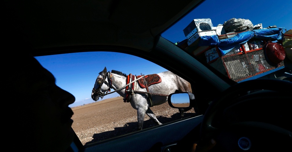 21.out.2014 - Comerciante conduz seu carrinho puxado por cavalo perto da passagem de fronteira de Mursitpinar, na cidade turca de Suruc, próximo à Síria