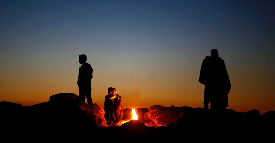 21.out.2014 - Curdos turcos se aquecem em torno de uma fogueira, na cidade síria de Kobani, perto da passagem de fronteira Mursitpinar, na fronteira turco-síria na cidade do sudeste de Suruc, na Turquia
