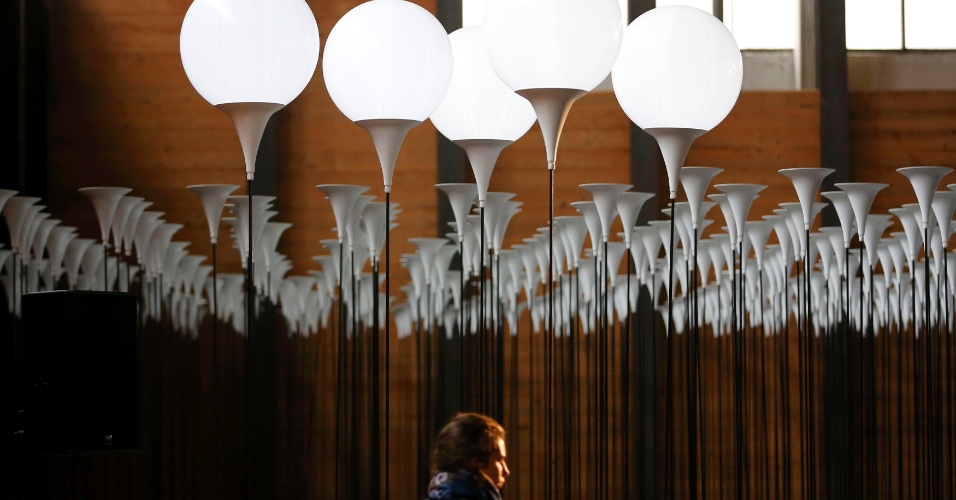 21.out.2014 - Mulher caminha entre estandes para balões de luz que serão utilizados na instalação 'Lichtgrenze' em um armazém em Berlim, na Alemanha