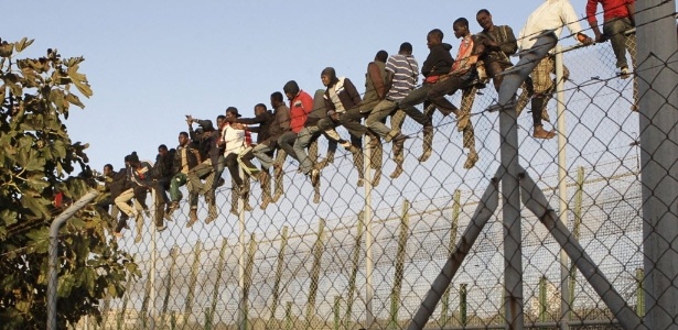 Imigrantes sentados em cerca na fronteira entre Melilha, na Espanha, e o Marrocos  - Francisco G. Guerrero/ EFE
