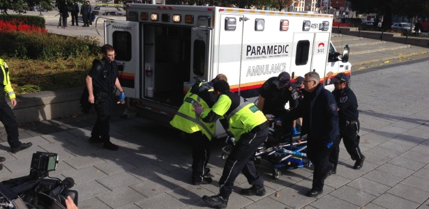 Policiais e paramédicos transportam homem ferido em tiroteio no Memorial da Guerra, em Ottawa, no Canadá - Michel Comte/AFP