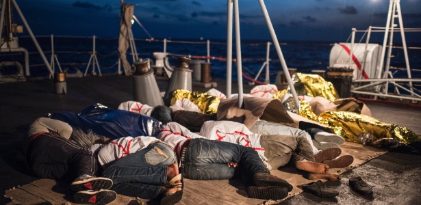 Imigrantes africanos descansam em navio enquanto são transportados pela marinha italiana após serem resgatadas no mar mediterrâneo, entre a Itália e a Líbia - Lynsey Addario/The New York Times