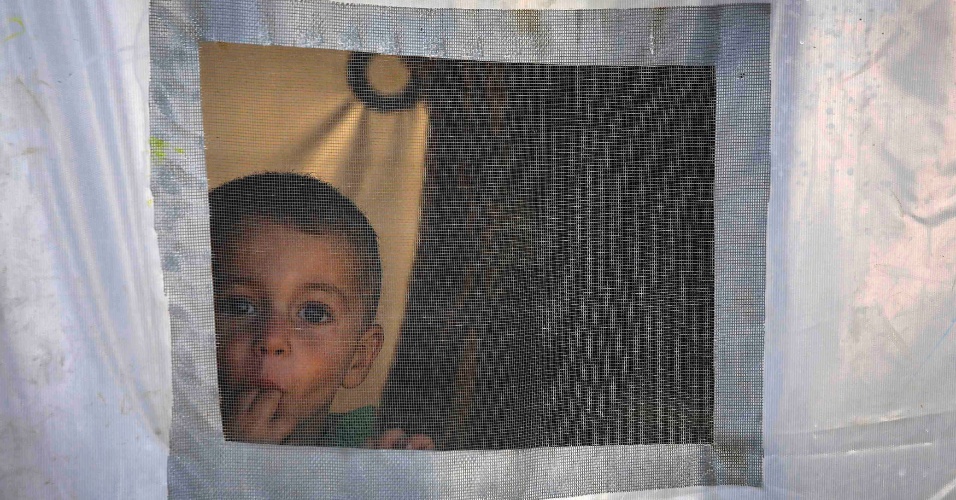 27.out.2014 - Um menino curdo  olha pela janela em uma barraca de um campo de refugiados na cidade fronteiriça de Kobani, na Turquia
