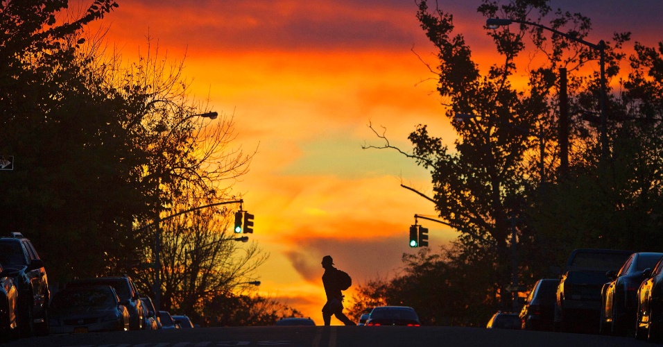28.out.2014 - Um homem atravessa a rua Leste 172 durante o pôr do sol no bairro do Bronx de Nova York (EUA)